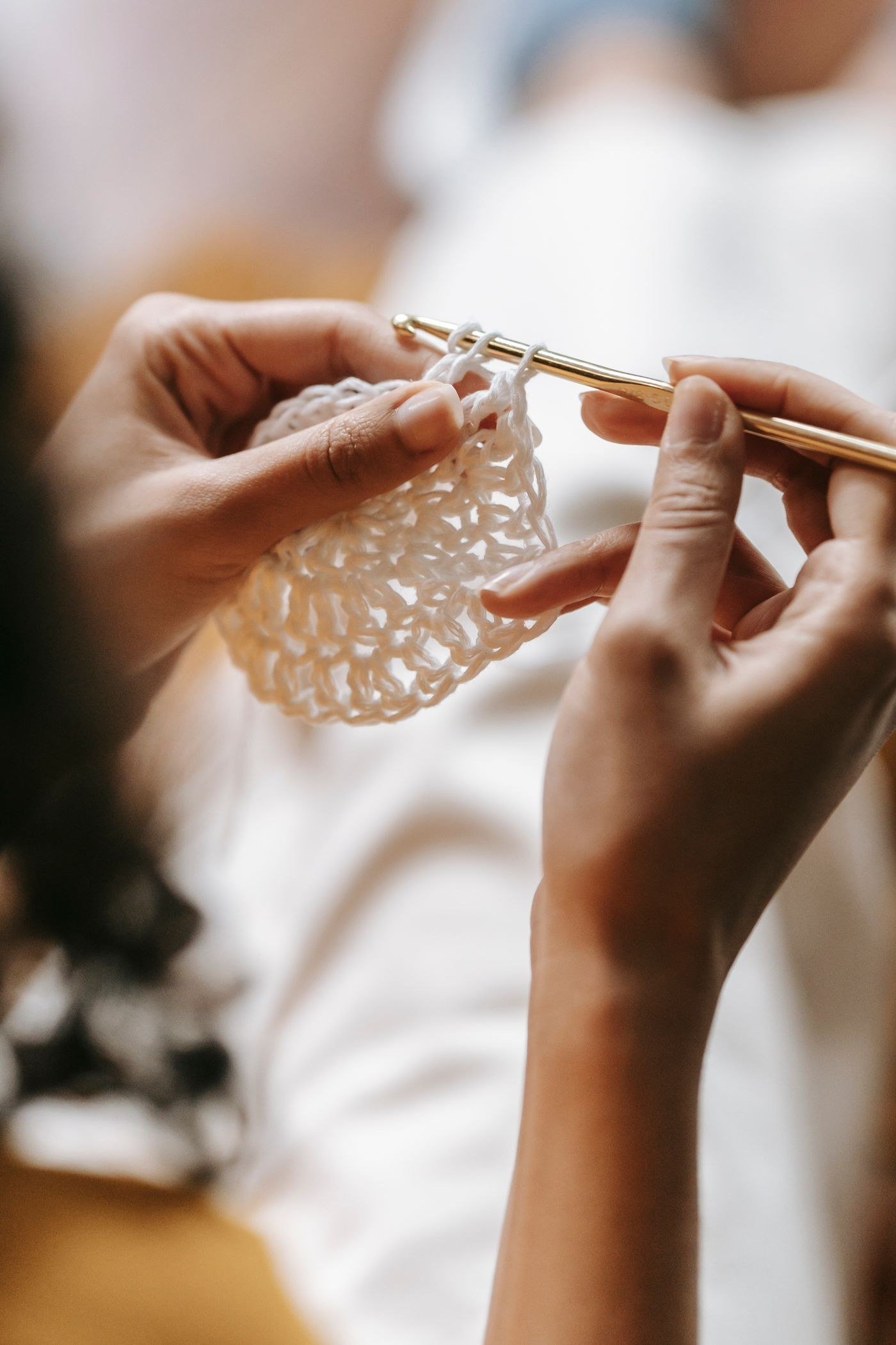Close-up of hands knitting and crocheting with white yarn