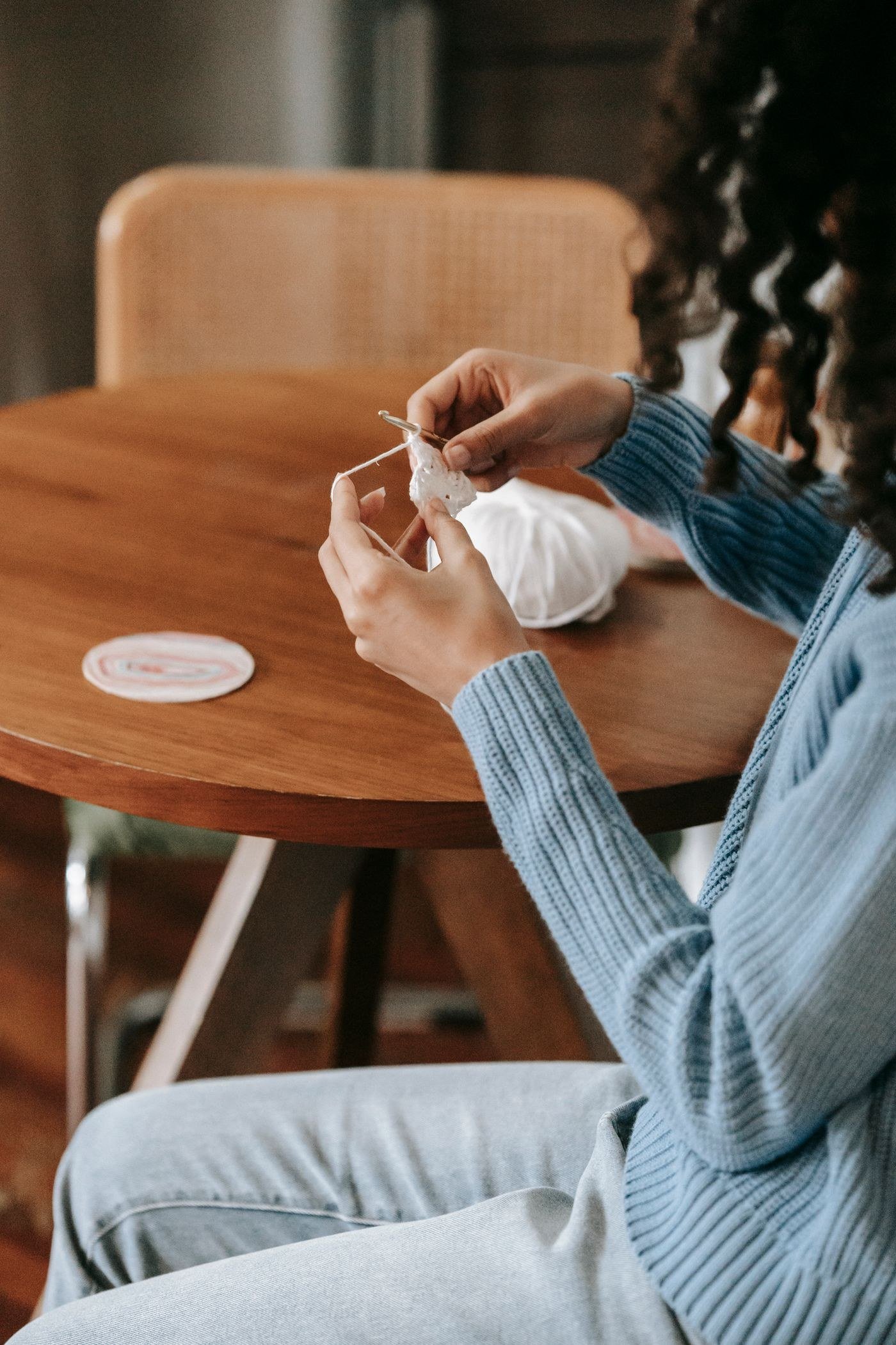 A woman crocheting at a wooden table