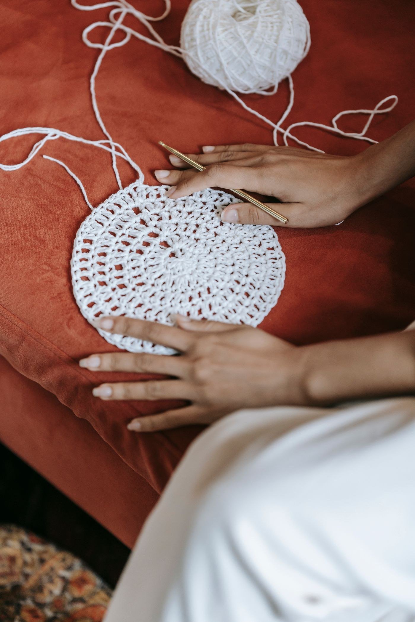 Hands crocheting a round motif in white yarn