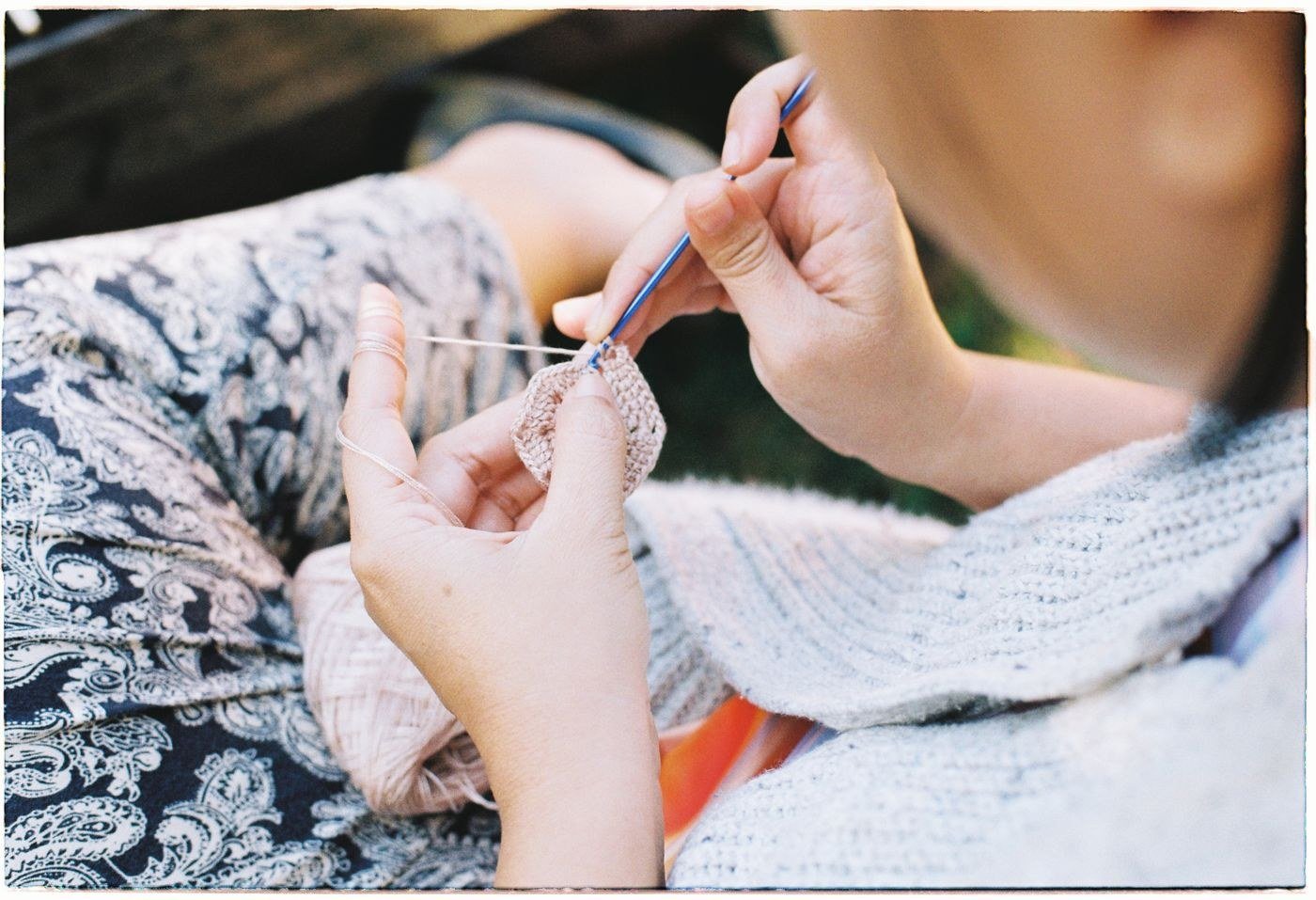A woman crocheting outdoors, close focus